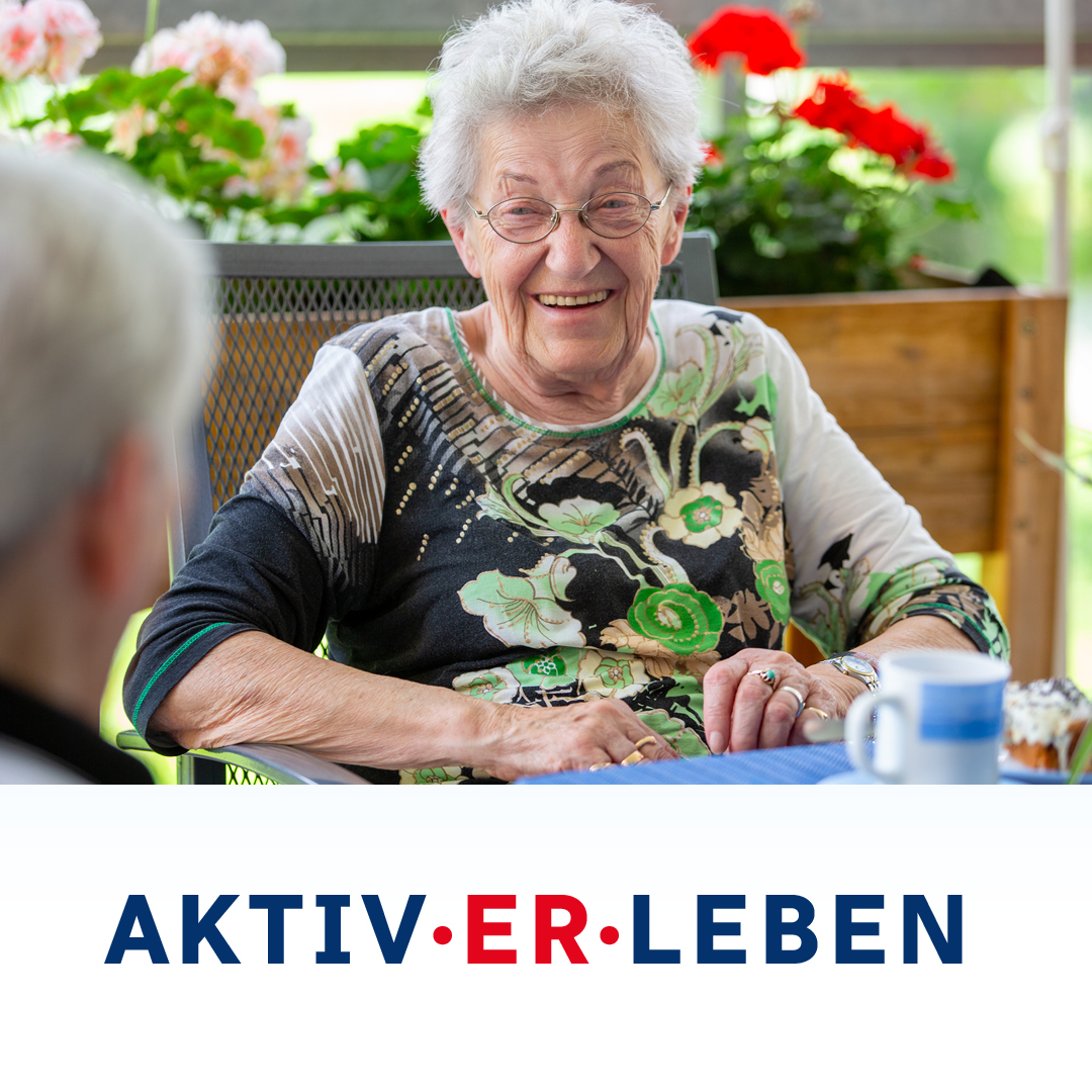 Lächelnde Seniorin in der Tagespflege der Geraer HBG in Gera; im Bild steht „Neuer Name – AKTIV·ER·LEBEN“.