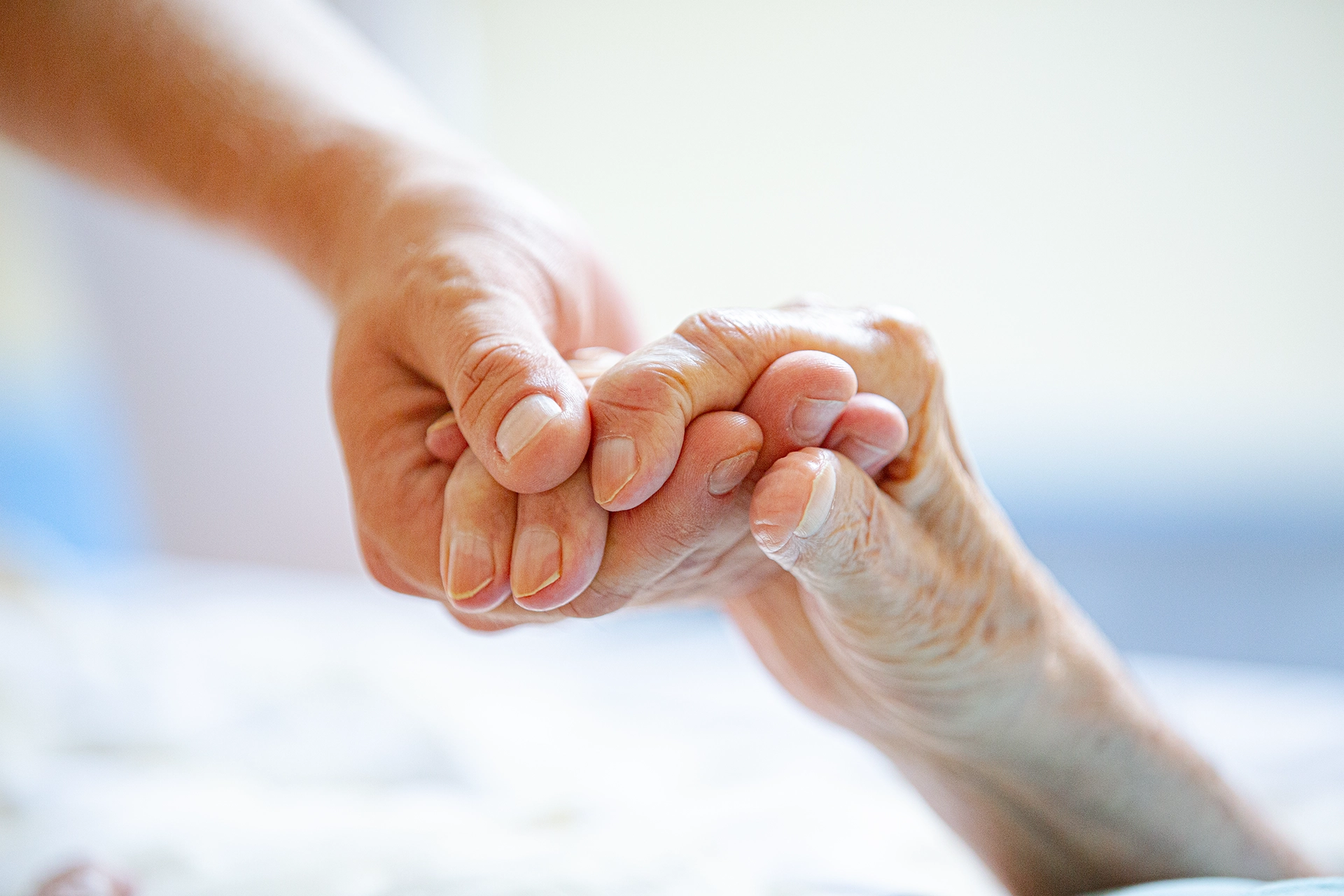 Junge Hand hält liebevoll die Hand einer älteren Person – Ausdruck von Fürsorge und Unterstützung.