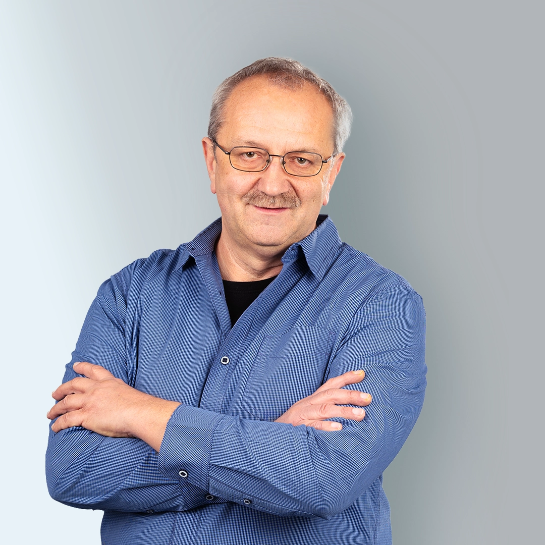 Porträt eines Mitarbeiters der Geraer Heimbetriebsgesellschaft mbH mit Brille und verschränkten Armen vor hellem Hintergrund