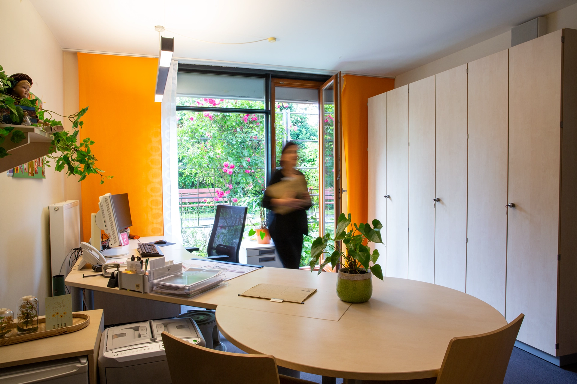 Eine Mitarbeitende verlässt ein freundliches Büro mit Blick ins Grüne.