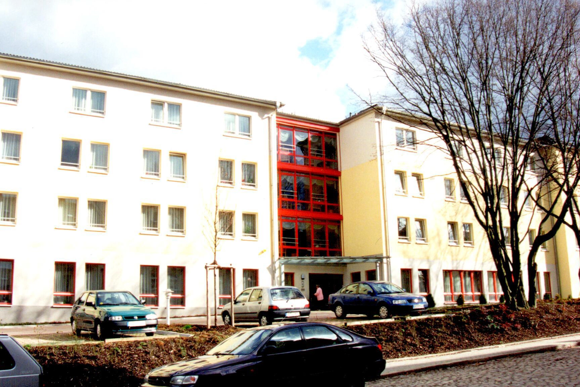 Fassade des Seniorenpflegeheimes „Colliser Straße“ mit Eingangsbereich und geparkten Autos davor.