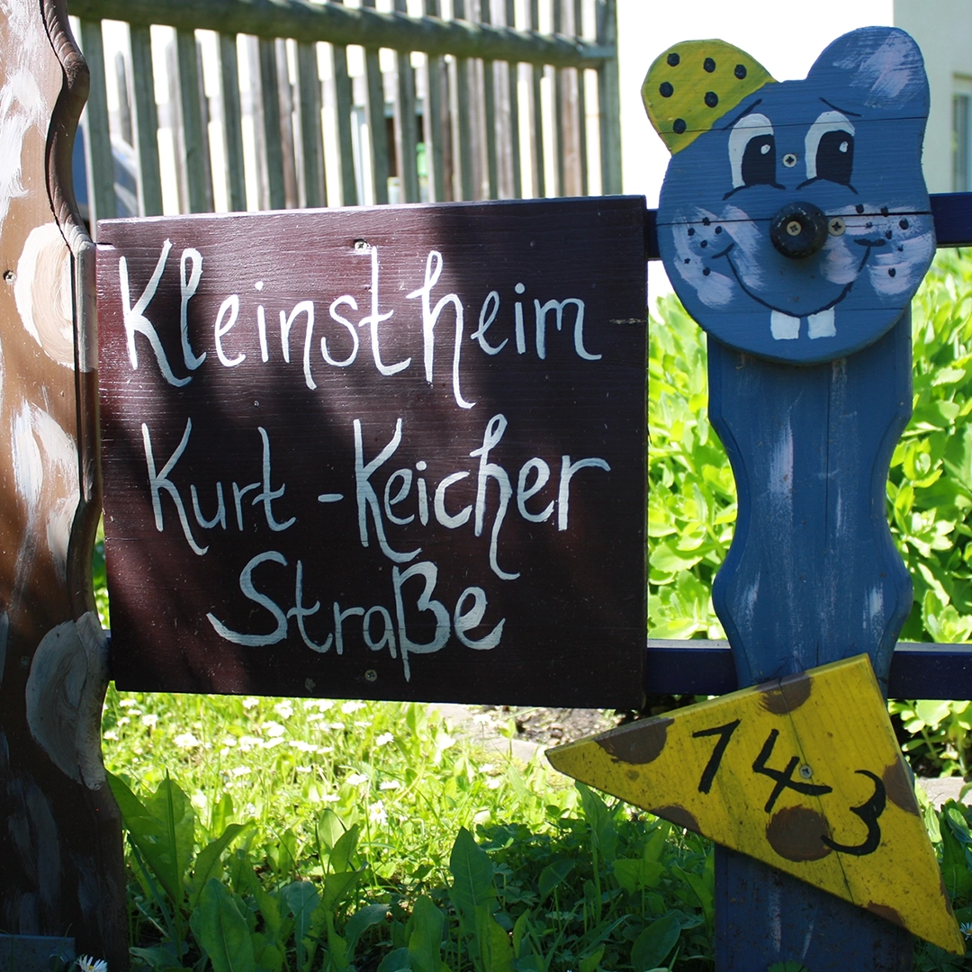 Holzschild zum Kleinstheim Kurt-Keicher-Straße in Gera mit bemalter Holzfigur – Aufnahme anlässlich des Richtfests im Jahr 2003.