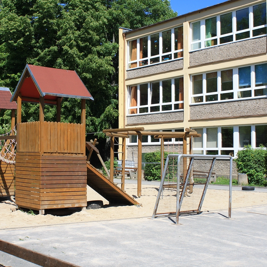 Außenansicht eines Schulgebäudes mit Spielplatz und Klettergerüst – 1996 eröffnete die Geraer HBG hier eine Tagesgruppe für Kinder im Grundschulalter.