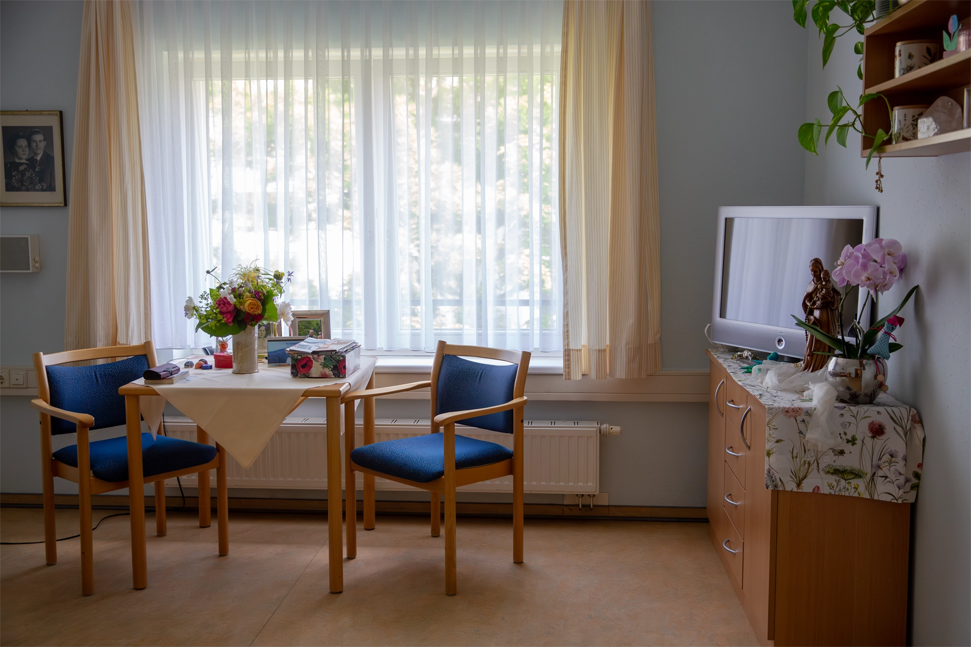 Helles Bewohnerzimmer mit Tisch, Stühlen und Fernseher.