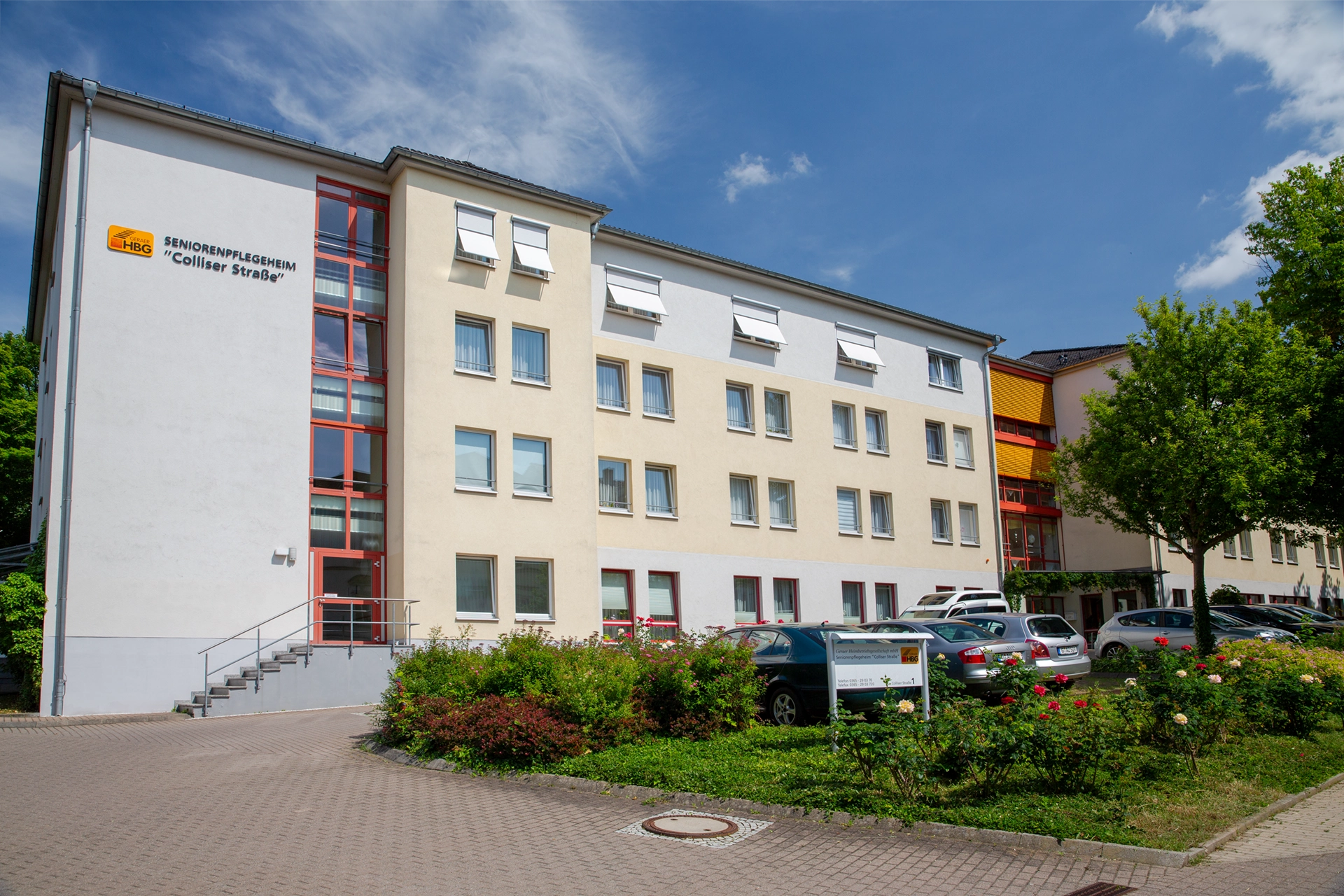 Außenansicht des Seniorenpflegeheims mit Garten und Parkplätzen.