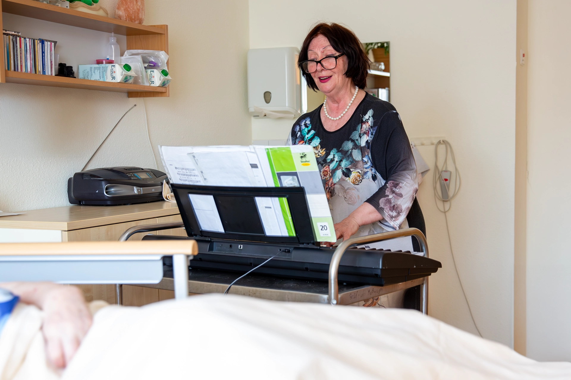 Eine Frau singt und spielt im Bewohnerzimmer auf einem E-Piano.