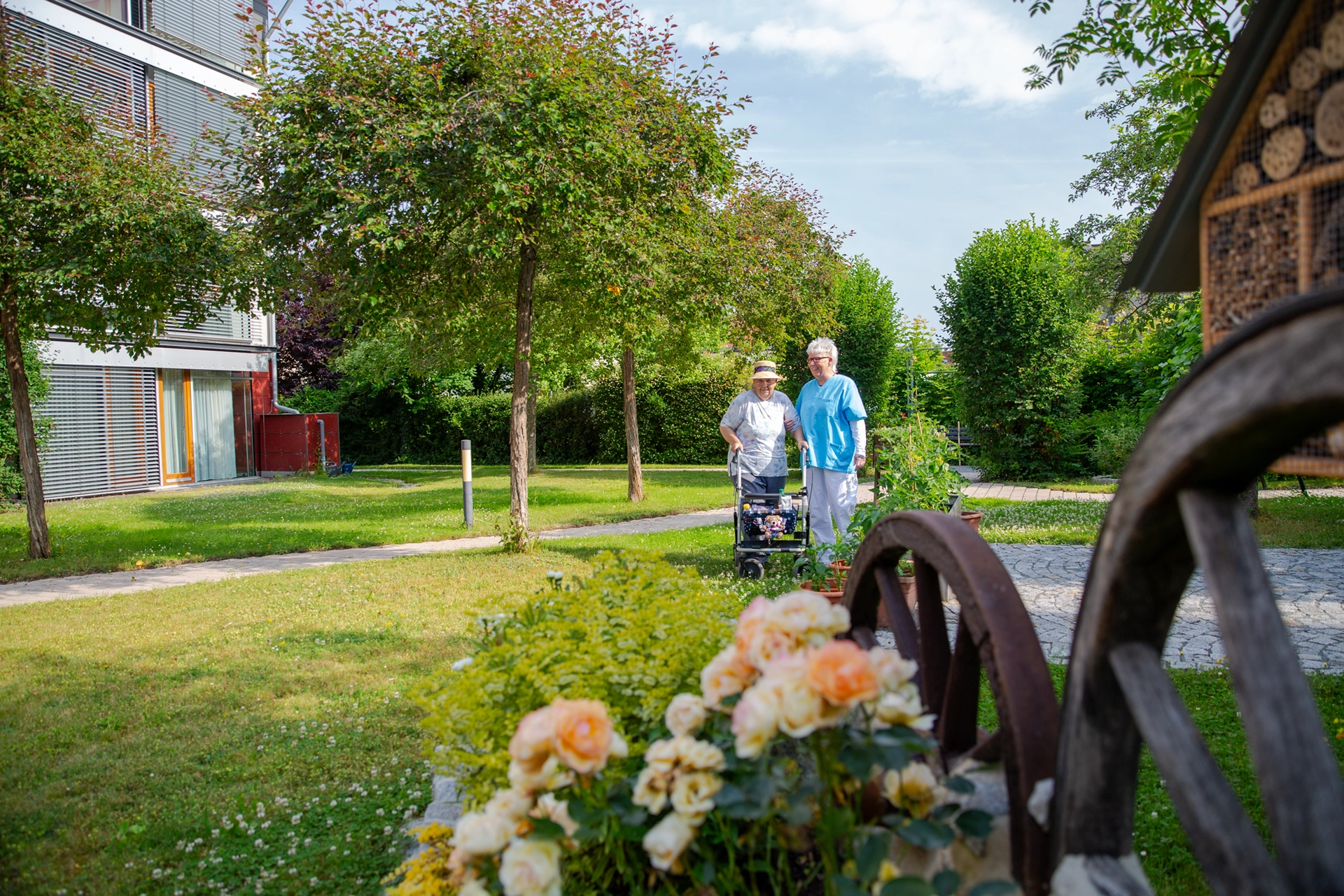 Seniorin mit Rollator und Pflegekraft beim Spaziergang durch den Garten des Pflegeheims Otto Dix der HBG Gera