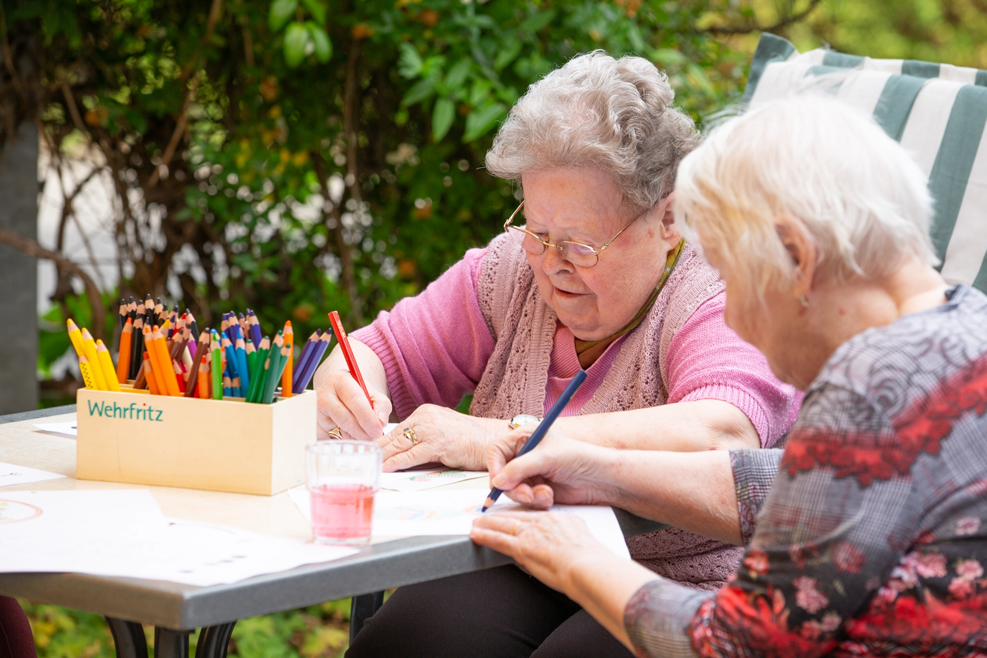 Zwei Seniorinnen malen mit Buntstiften im Garten des Pflegeheims Otto Dix der HBG Gera