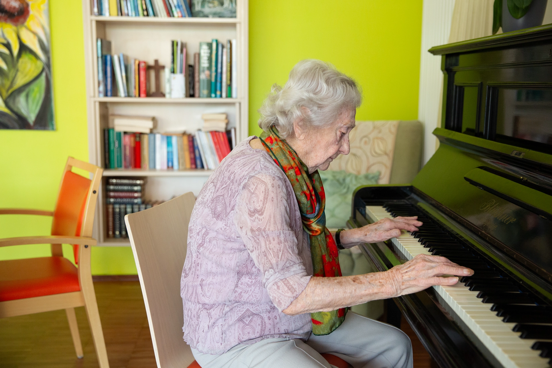 Bewohnerin spielt Klavier in einem hellen Gemeinschaftsraum des Pflegeheims Otto Dix der HBG Gera