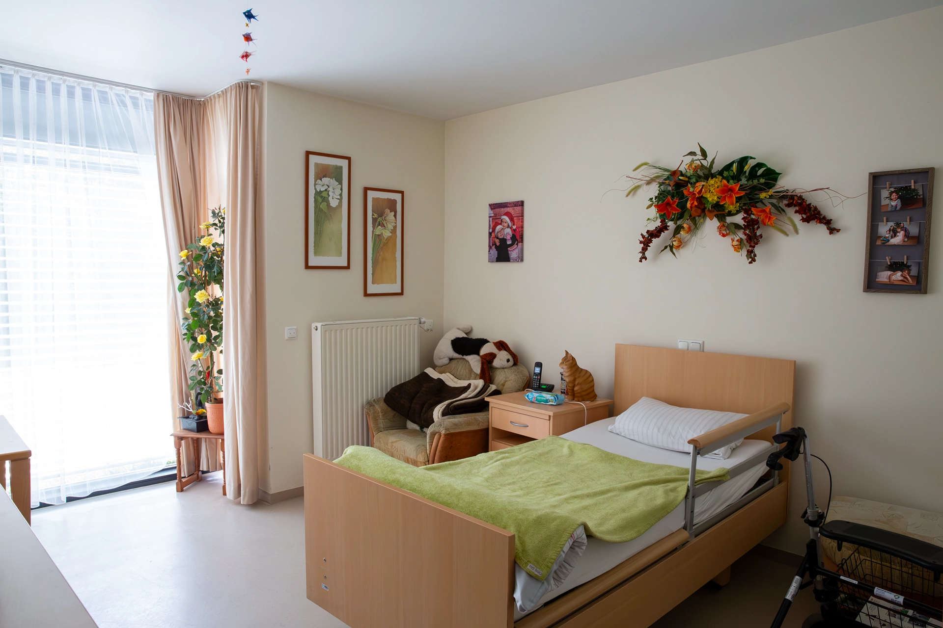 Ein heller Bewohnerraum mit Pflegebett, gemütlichem Sessel und Pflanzen