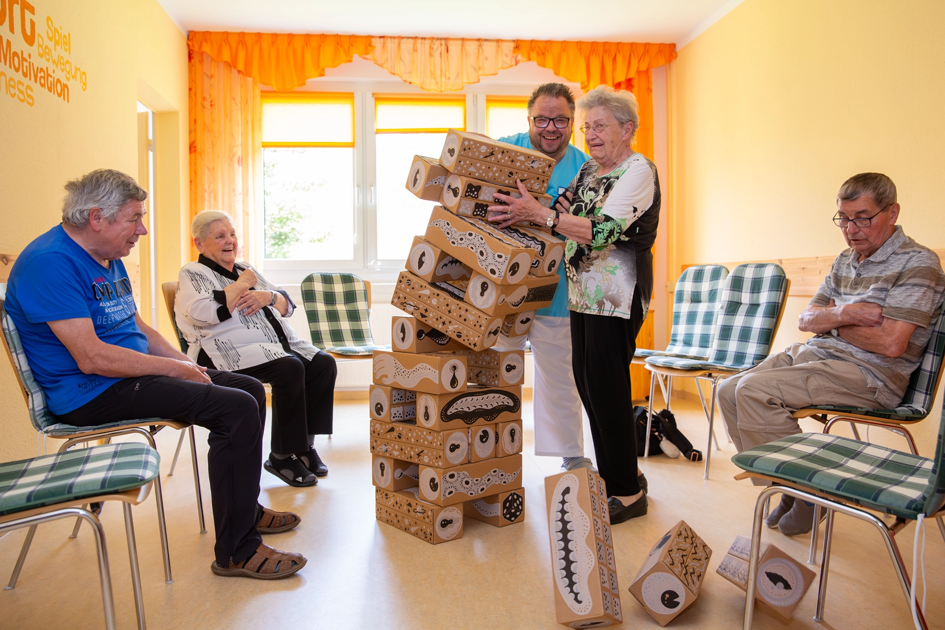 Senioren und Betreuer spielen gemeinsam mit großen Holzbausteinen in einer Tagespflege der HBG Gera